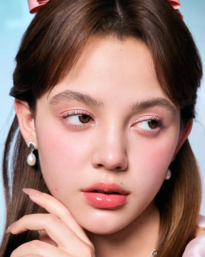 Close-up of a person with styled hair and makeup against a light blue background